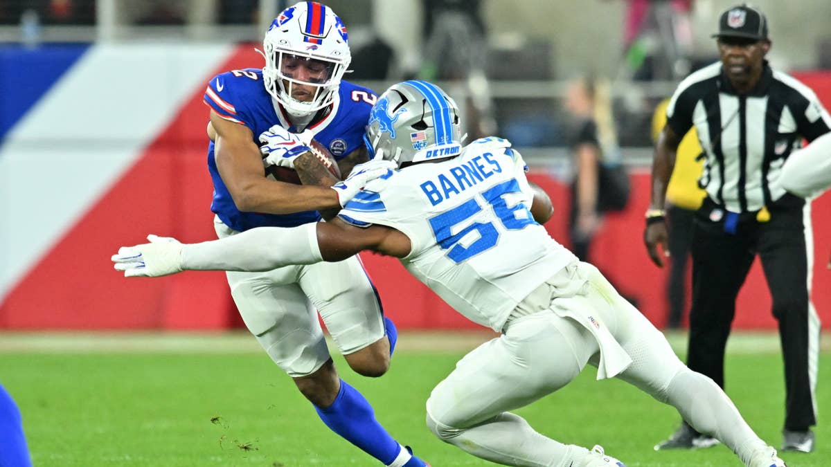 Bills WR DJ Moore #2 in blue jersey tackled by Lions player Barnes #56 in white jersey.