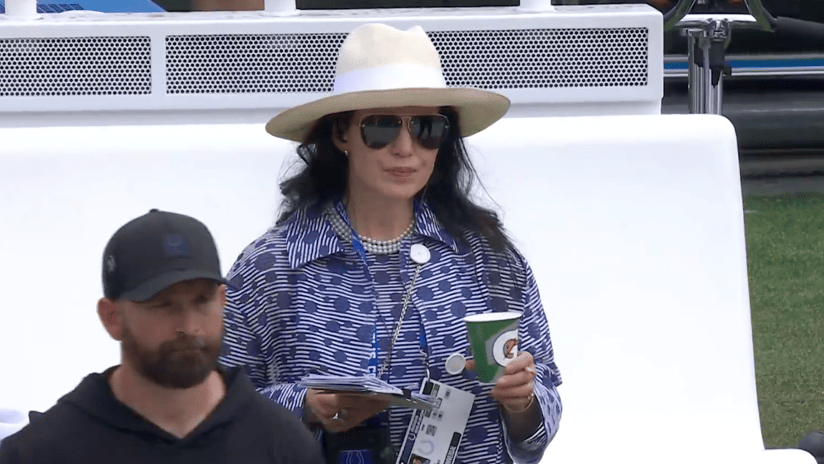 Carlie Irsay-Gordon in a blue patterned jacket and hat holds a drink at a Colts game.