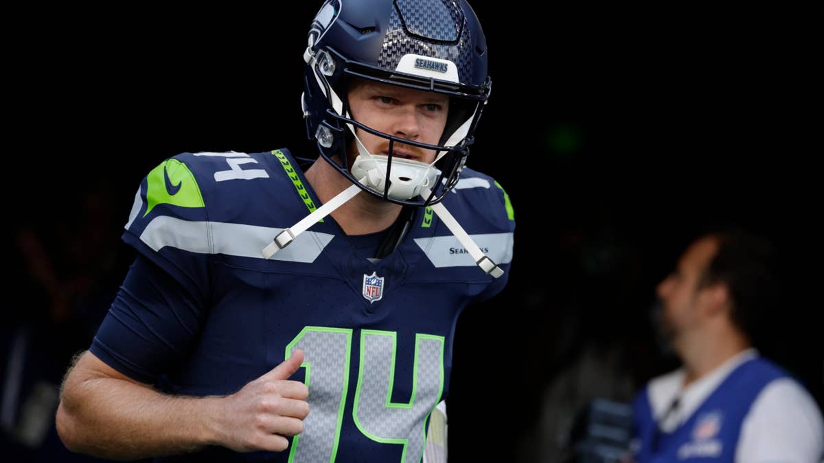 Sam Darnold in a Seahawks #14 jersey and helmet runs out of a tunnel.