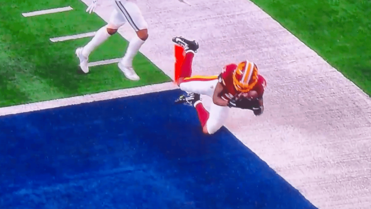 Washington Commanders player in maroon and gold dives for a touchdown against the Cowboys.