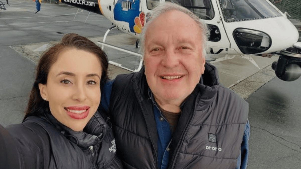 Eliana Moreno and George Marciniw smile in front of a helicopter with "BCLA.com" visible.