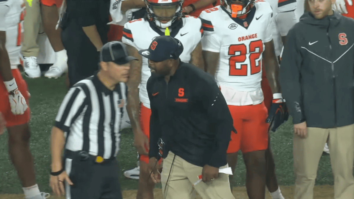 Fran Brown argues with a referee near Syracuse players in orange and white uniforms.