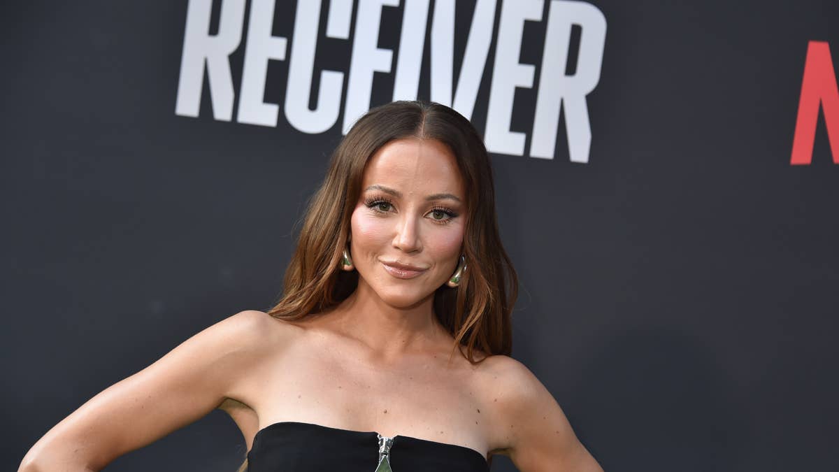 Kay Adams in a black strapless top with large hoop earrings, posing in front of a dark background with white text.