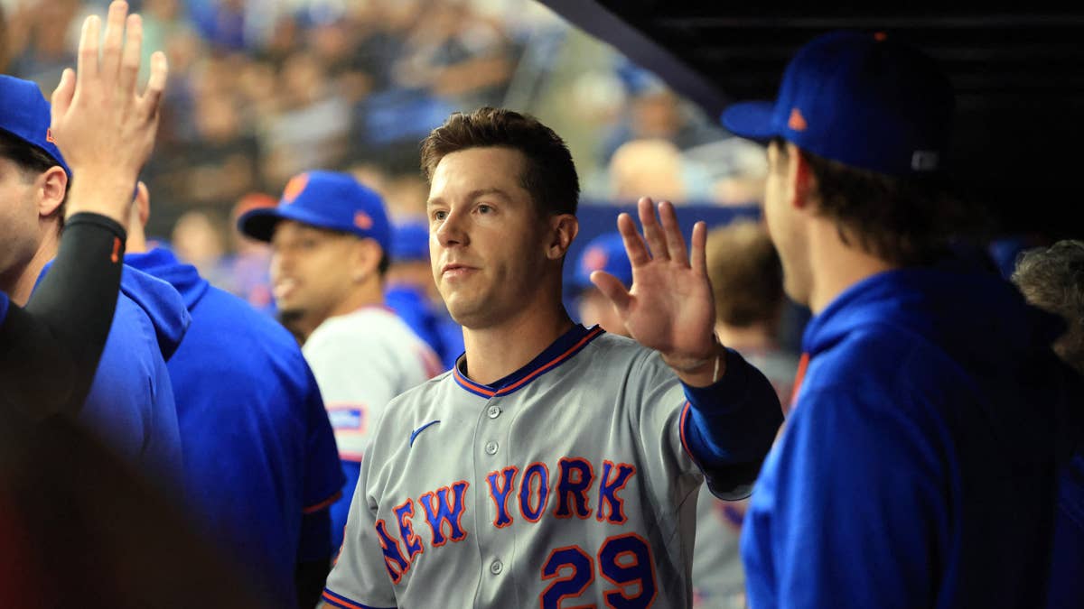 Jared Young in a New York Mets gray jersey number 29 waves in the dugout.