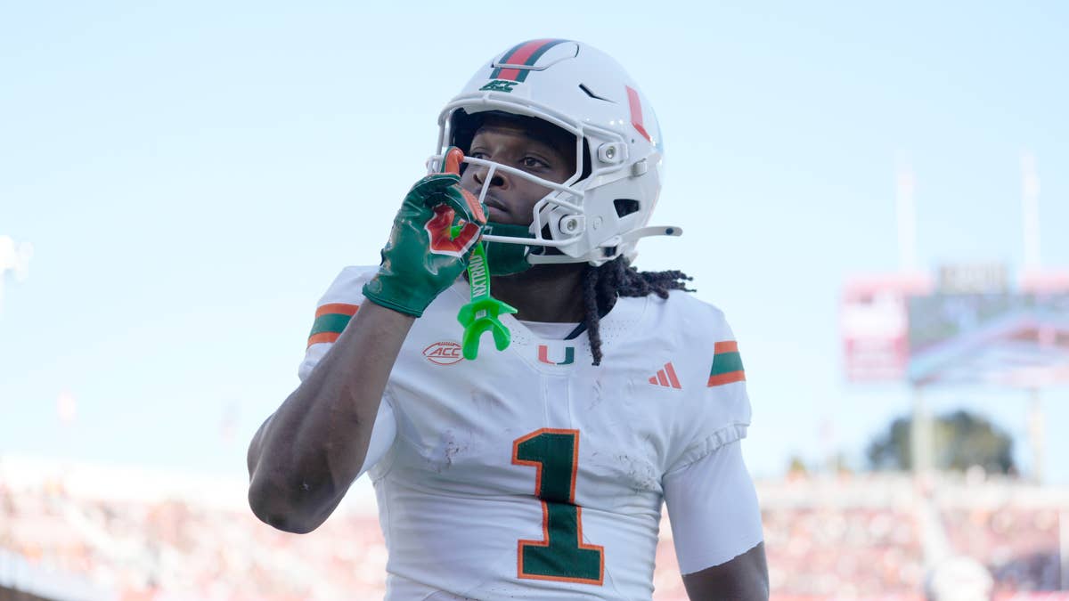 Miami Hurricanes player with number 1 on white jersey with orange and green stripes, holding green mouthguard.