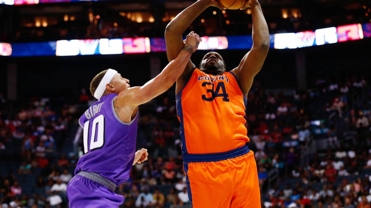 Michael Sweetney (34) in orange and a player in purple (10) play basketball.