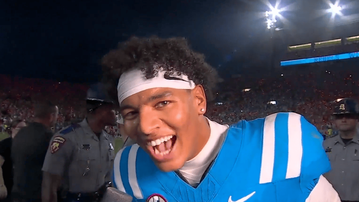 Ole Miss QB Trinidad Chambliss in a blue and white jersey with a white Nike headband smiles widely.