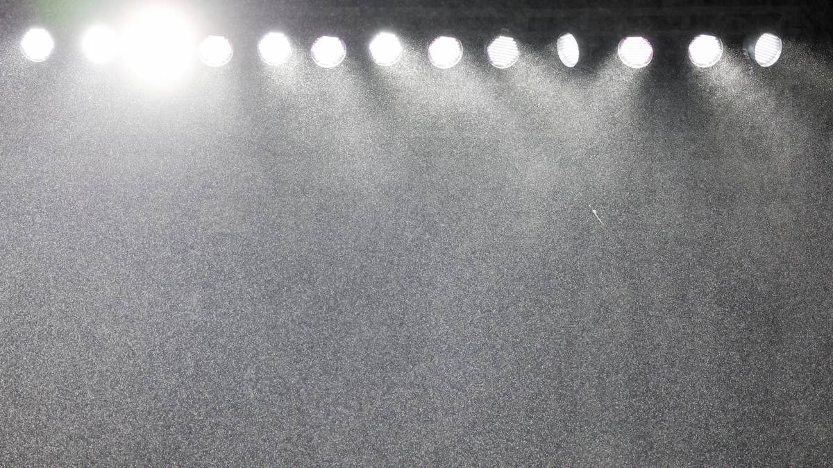 Stadium lights shine down on a misty, gray field.