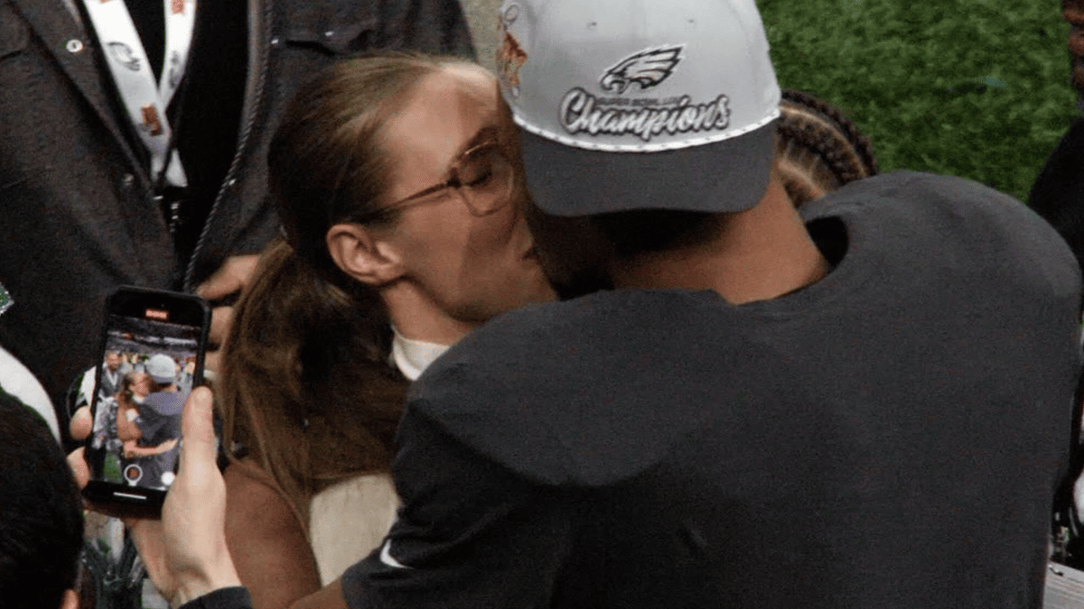Saquon Barkley kisses fiancée Anna Congdon, wearing an Eagles Super Bowl Champions hat.