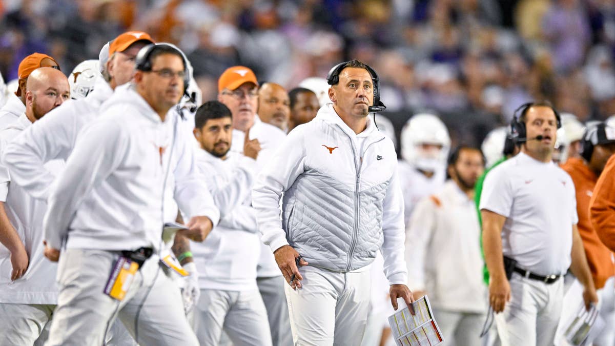 Texas Longhorns coaches in white hoodies and pants on the sideline.
