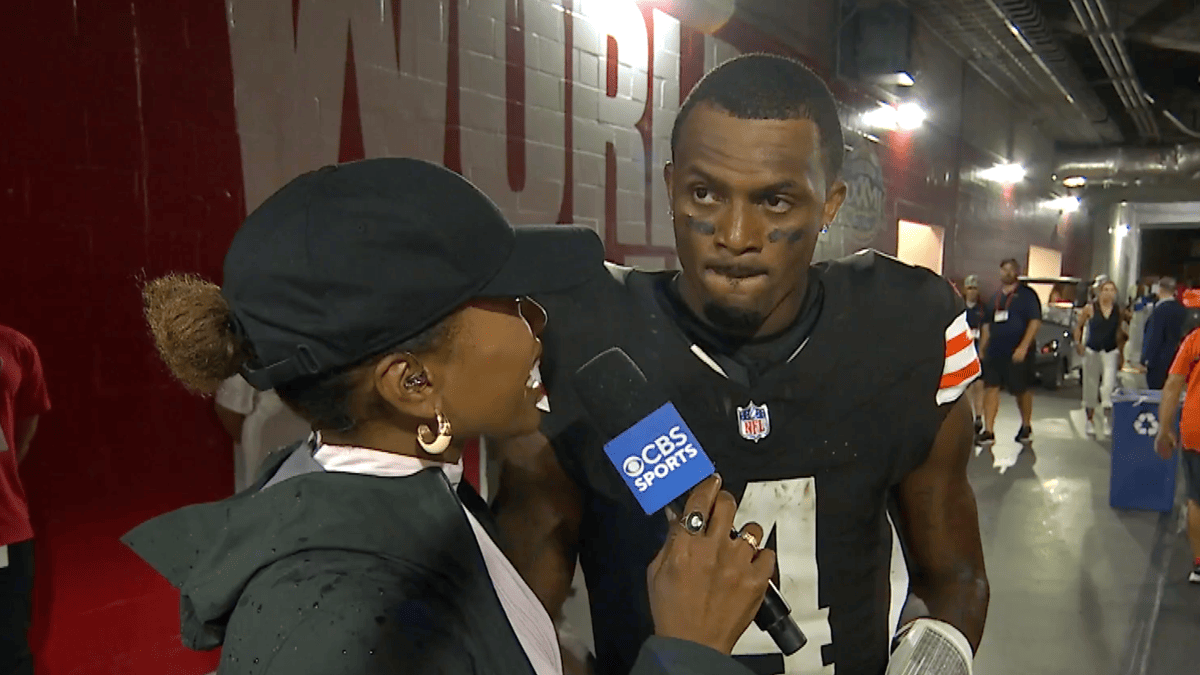Deshaun Watson in a brown Browns jersey with orange stripes is interviewed by a reporter holding a CBS Sports microphone.