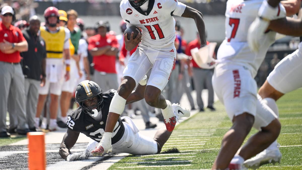 CJ Bailey #11 in white NC State uniform fumbles as #32 in black uniform tackles him.