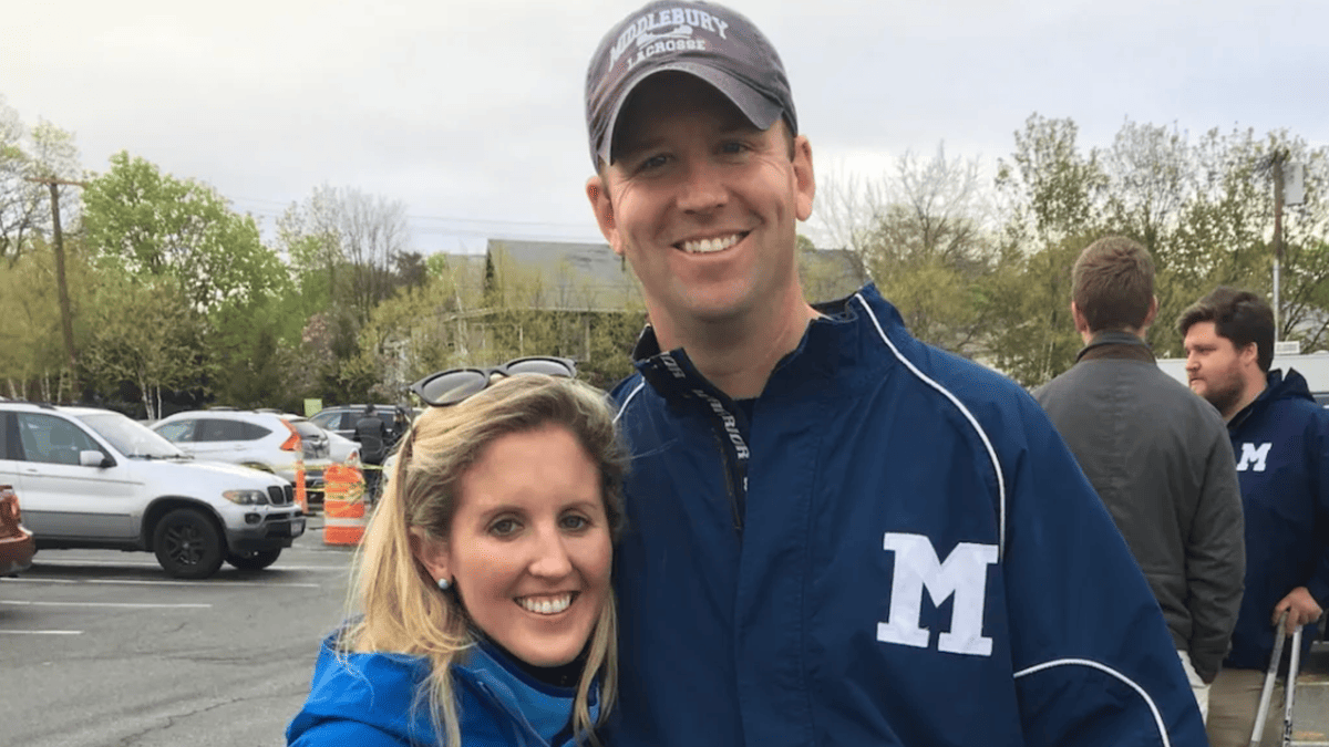 Emily McNamara and a man in a Middlebury Lacrosse hat and blue jacket with an M logo, with others in the background.